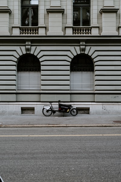 Black motorcycle parked near the white building
